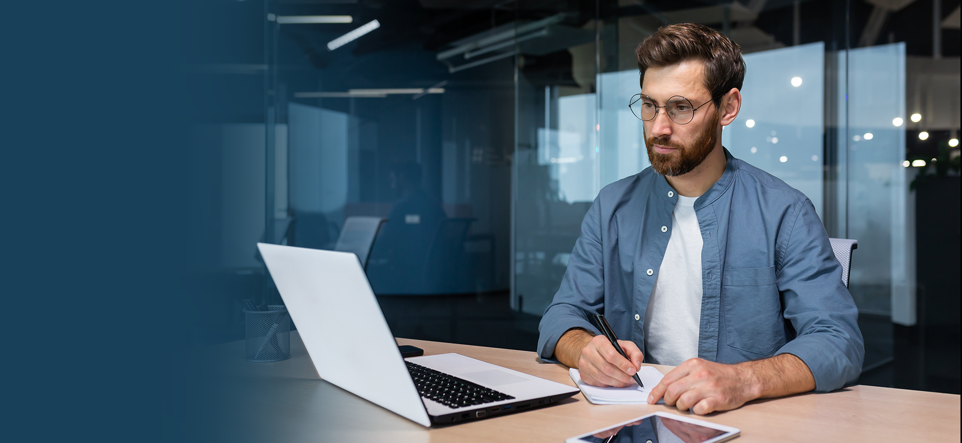 mężczyzna przy komputerze robiący notatki 