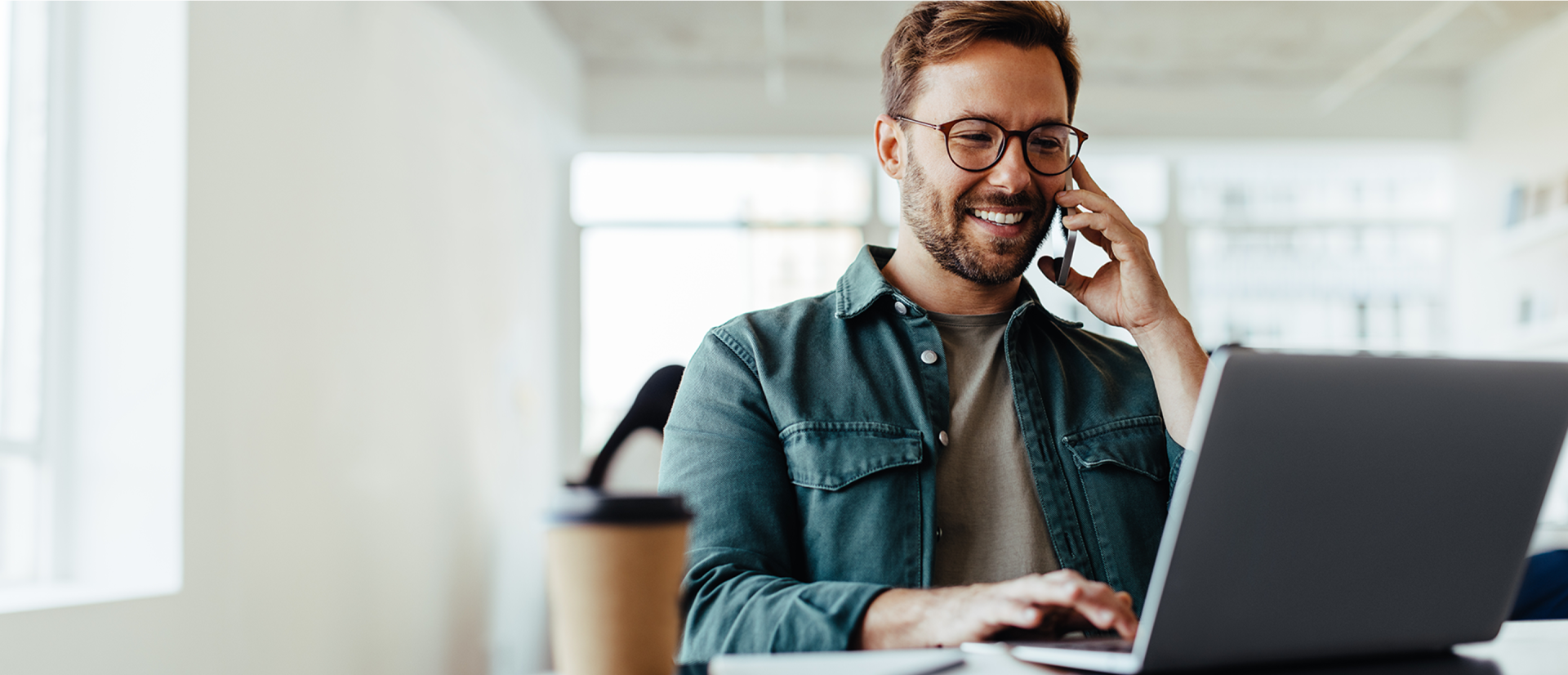 pracownik rozmawiający przez telefon przy komputerze