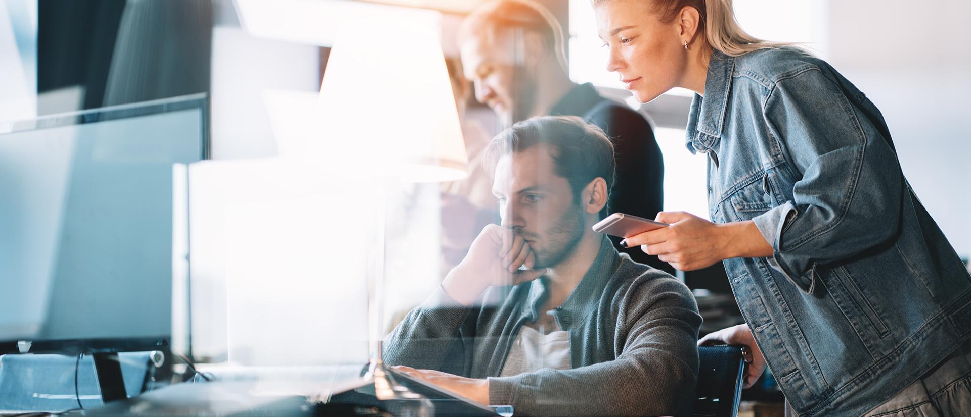 Grupa pracowników omawiająca zadanie przed laptopem