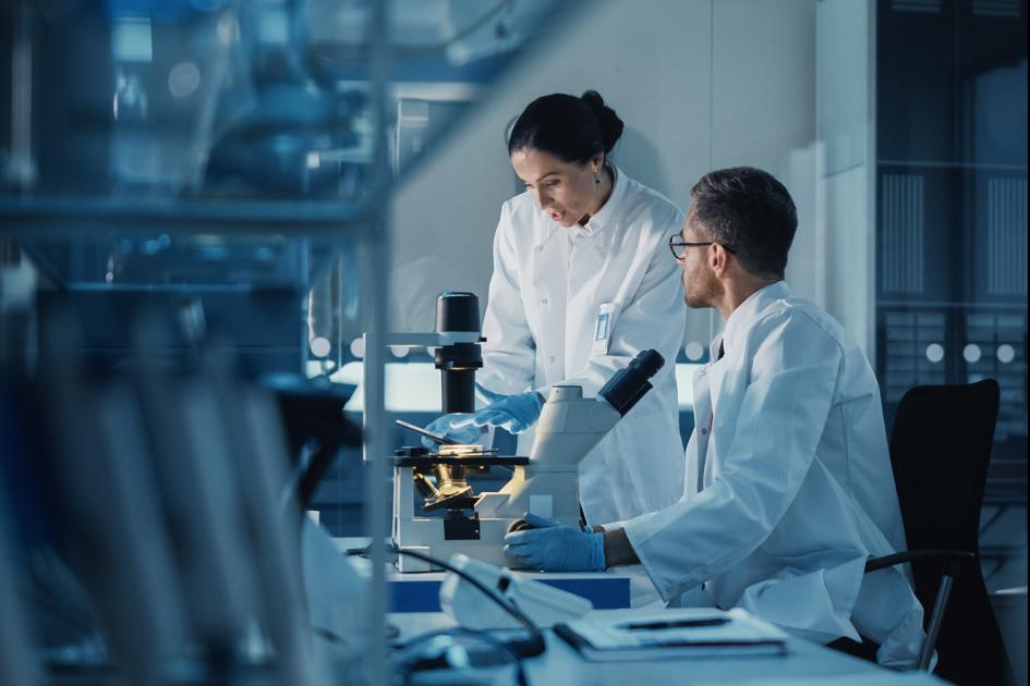 Dwoje diagnostów laboratoryjnych pracujących przy aparaturze